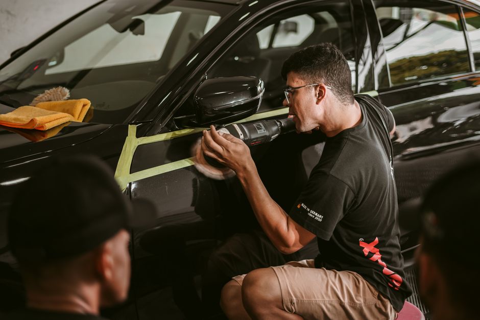 Professional auto detailer carefully polishing vehicle exterior